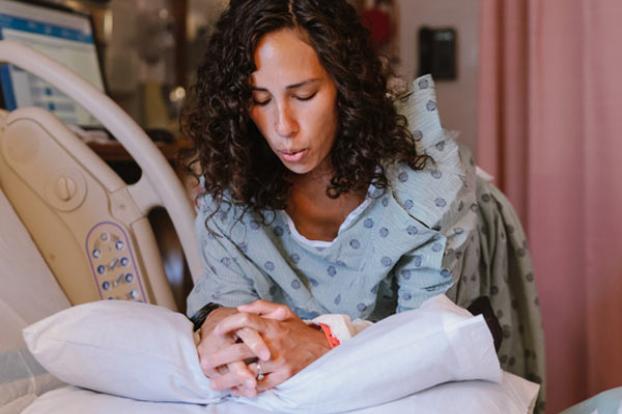 Mom in labor breathing while leans on pillows.