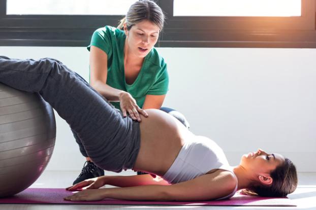 Pregnant with physical therapist on floor mat and ball.