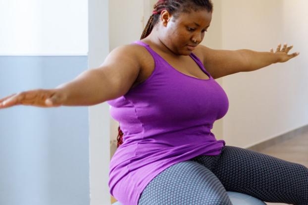 Physical therapy sitting on a large ball with hands out.