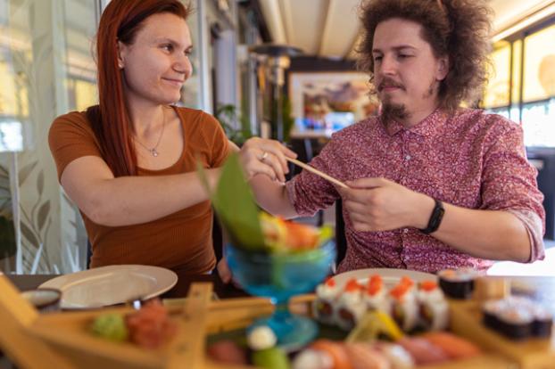 Couple eating sushi with chopstick.