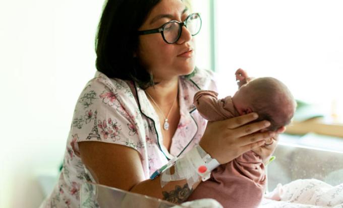 Mom and newborn beside bassinet