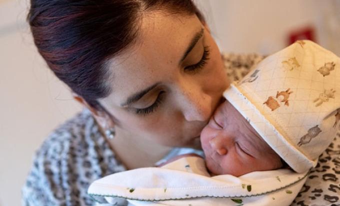 Mom kissing newborn in cap