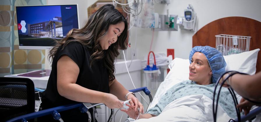 Nurse placing pulse oximeter on patients finger.