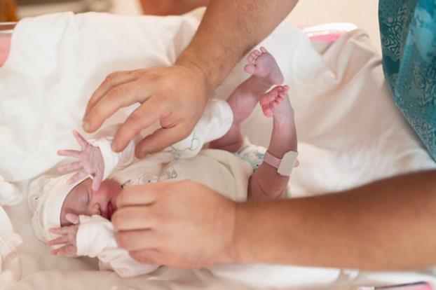 Dad dresses newborn.