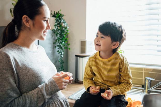 Pregnant mom eating satsuma with child.