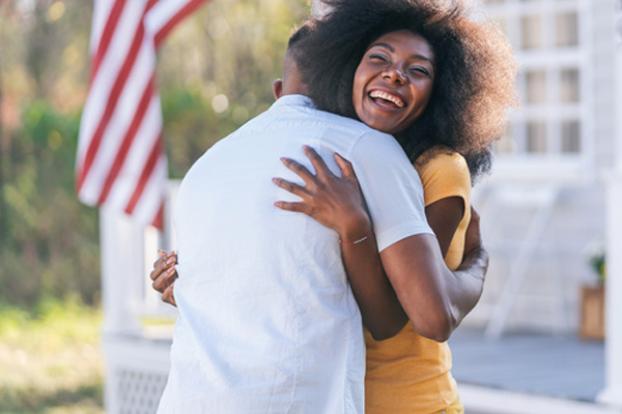 Couple happy big hug outside with flag.