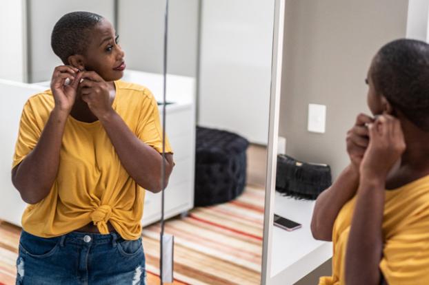 In dressing room mirror adjusting earring.