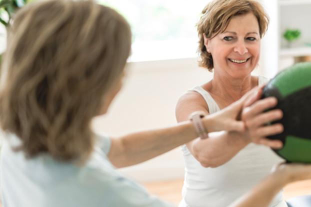 Holding ball out with physical therapist's help.