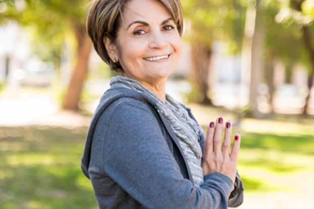 Cancer patient outside with hands at heart. 