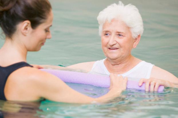 Aquatic therapist with patient and pool noodle.